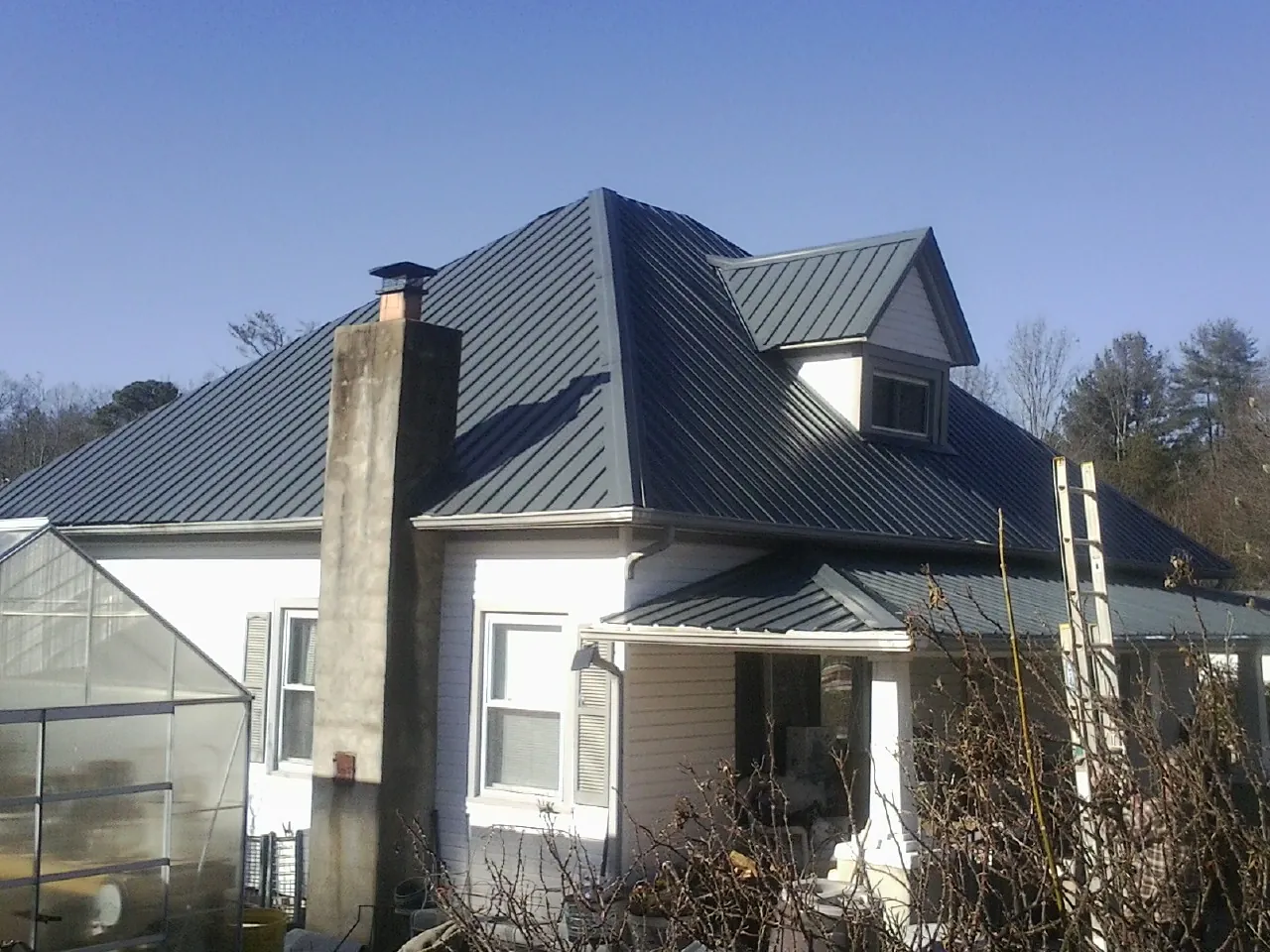 Dark blue standing seam metal roof on a white farmhouse with dormer — Slate & Tile Roof Repair by Roofing Brothers in Exira