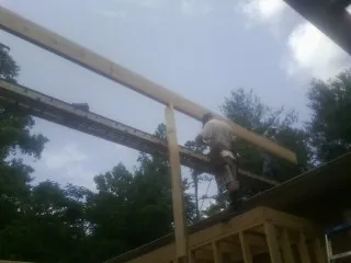 Carpenter setting a ridge beam over a new addition frame — Ice Dam Removal by Roofing Brothers in Exira