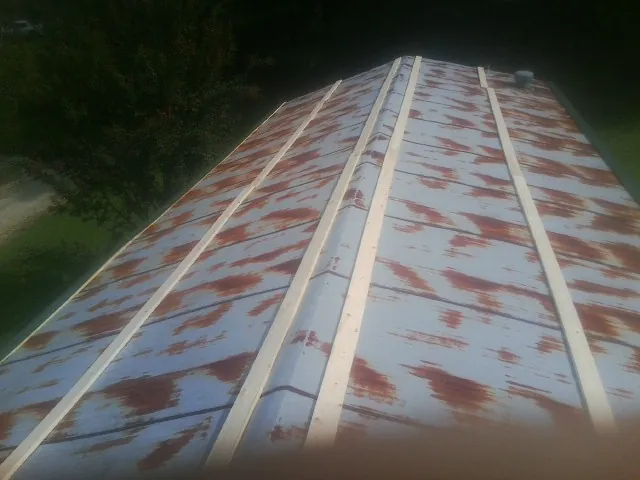 Rusted metal roof panels with new wood purlins before replacement — Storm Damage Roof Repair in Exira by Roofing Brothers