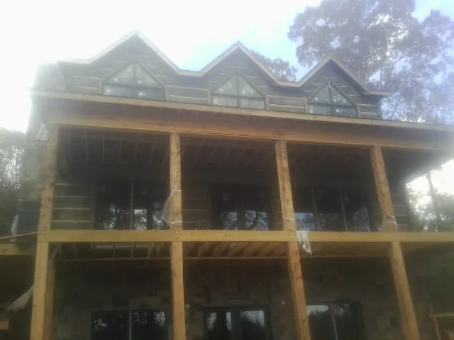 Dormers and porch framing on a large log home under construction — Roof Coating work by our crew in Exira