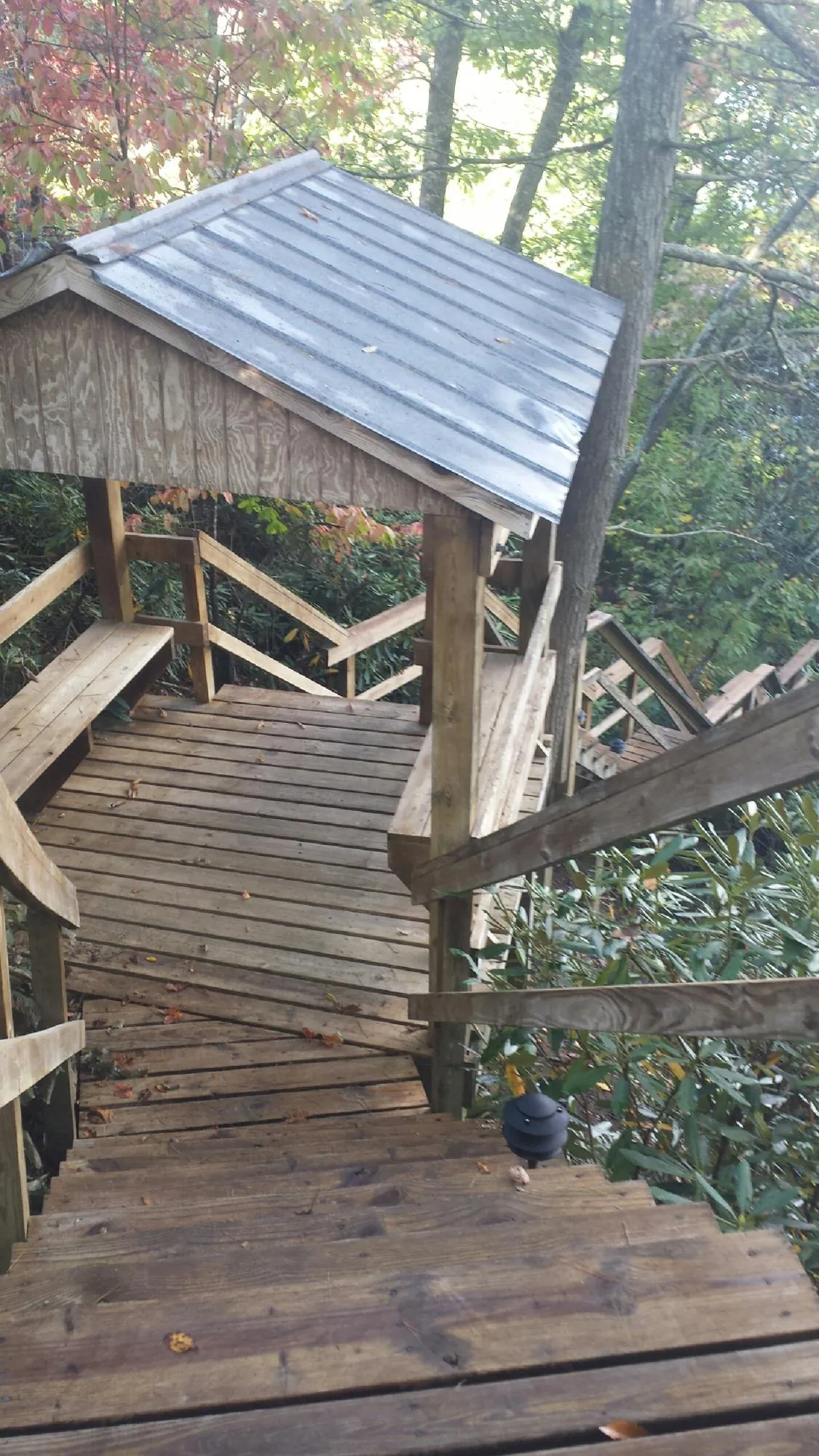 Metal roofed shelter over wooden steps on a wooded walkway — Skylight Repair & Installation work by our crew in Exira