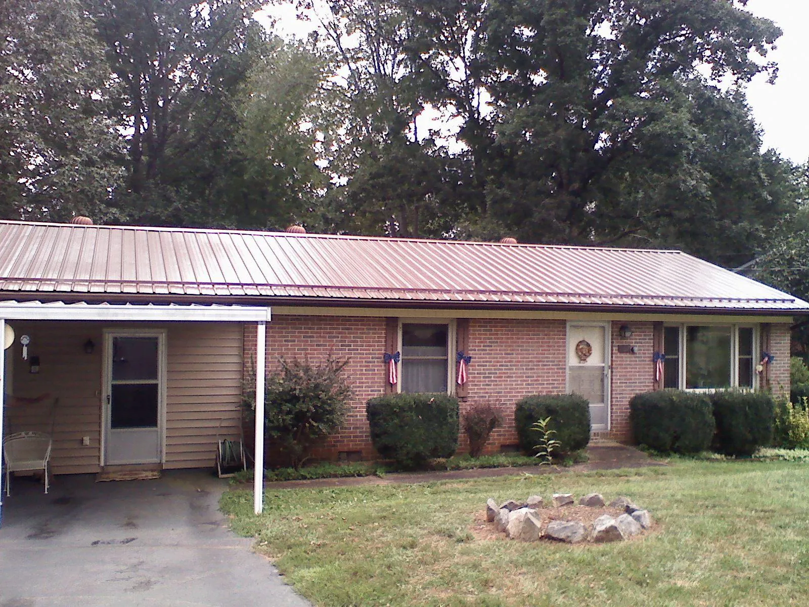 Bronze metal roof and carport on a brick ranch home — Roof Repair work by our crew in Exira
