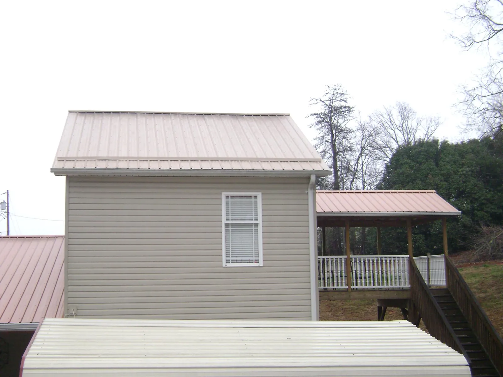 Tan metal roofs on a two story addition and attached porch, from a Roof Replacement job in Exira