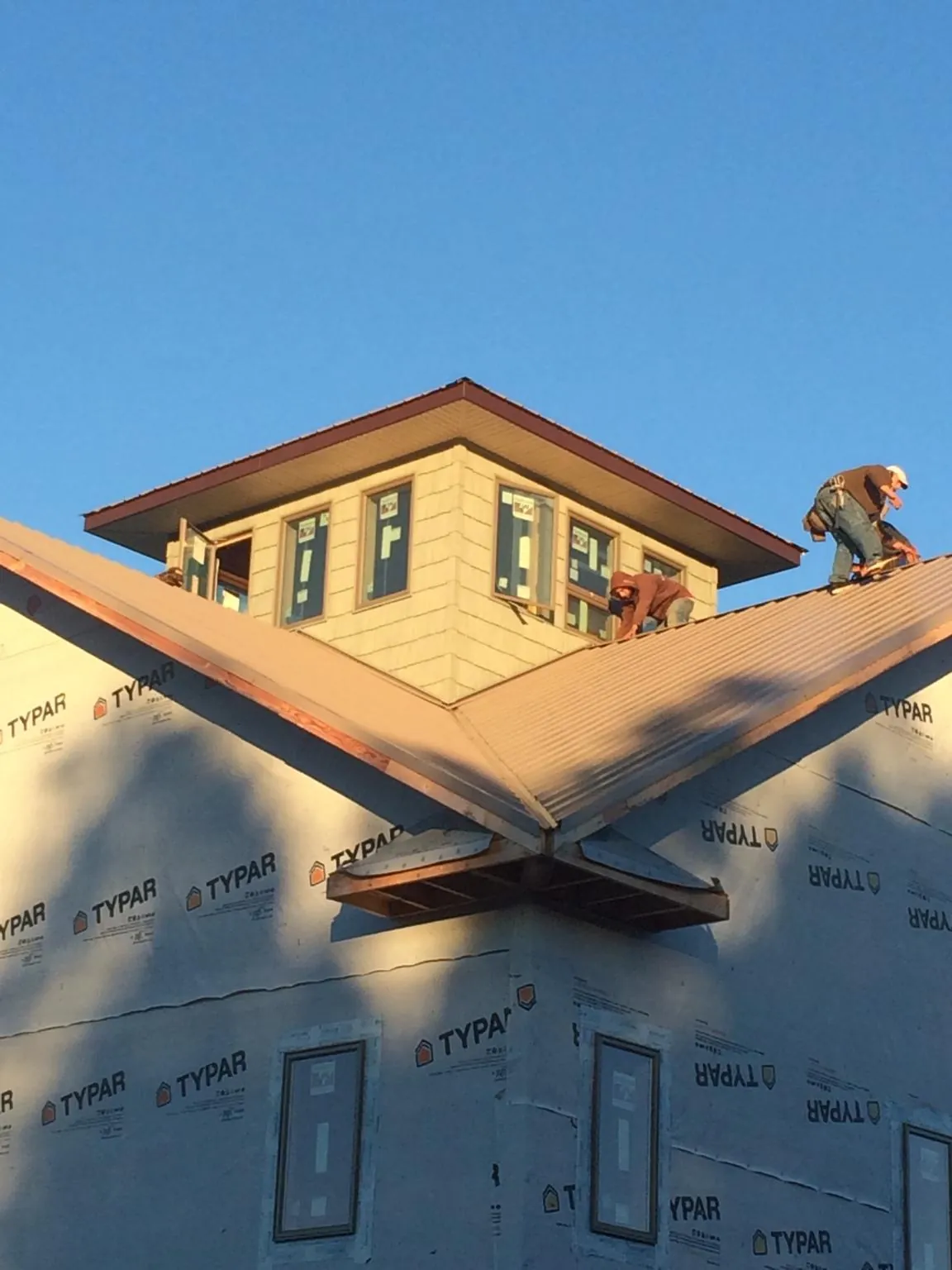 Roofers working around a rooftop cupola on a new metal roof at sunset — Roof Waterproofing in Exira by Roofing Brothers